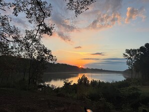 Un atardecer sobre un lago con árboles en sus orillas.