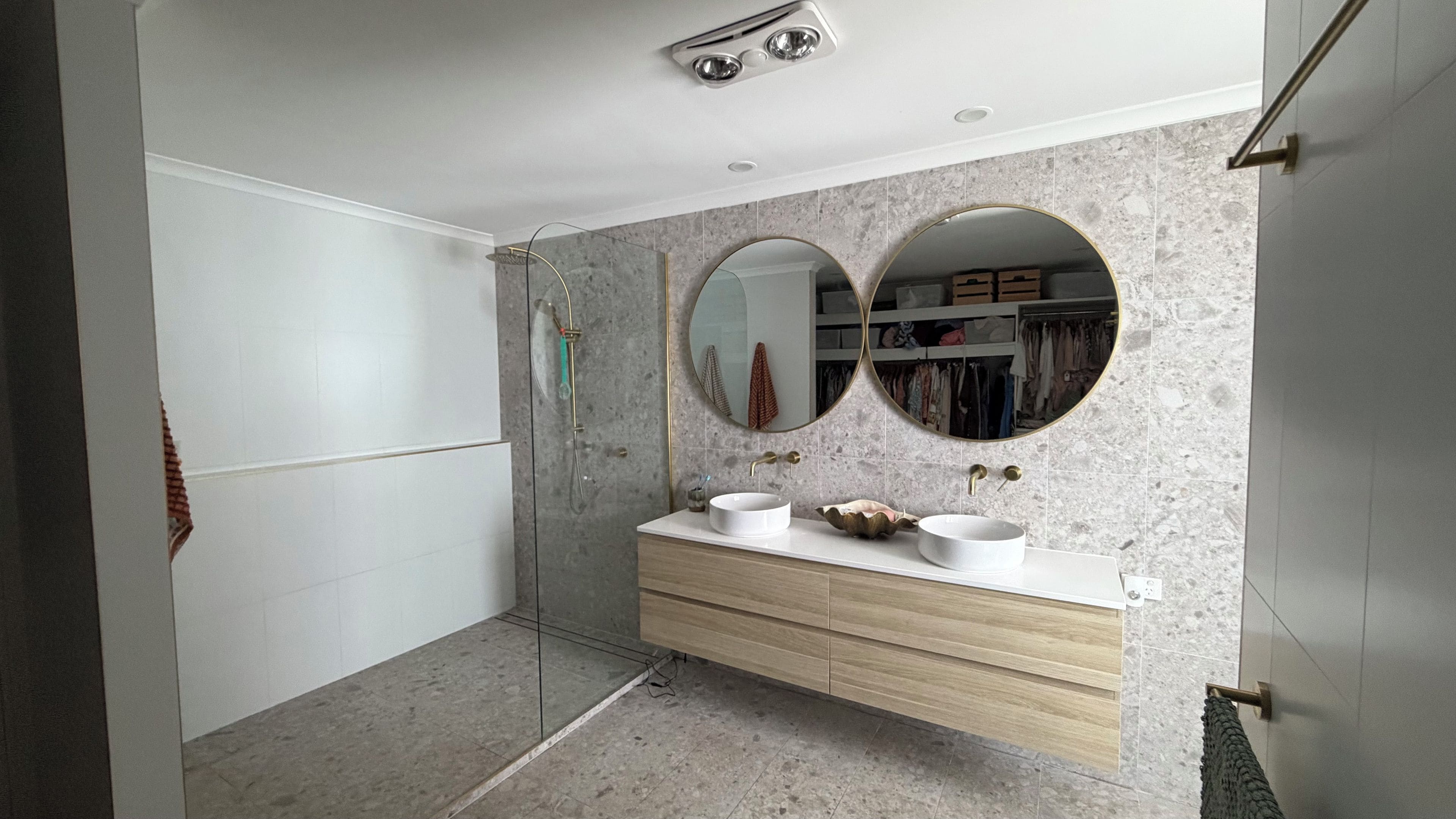 Un baño moderno con tocador doble lavamanos, un espejo grande y cabina de ducha.