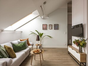 A modern living room with a sofa, coffee table, and a TV. - Barbican Apartments by Fragola (Kraków)