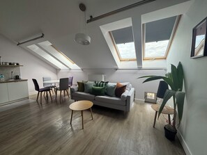 A modern loft apartment with skylights, a dining area, and a living space with a sofa and chairs. - Barbican Apartments by Fragola (Kraków)