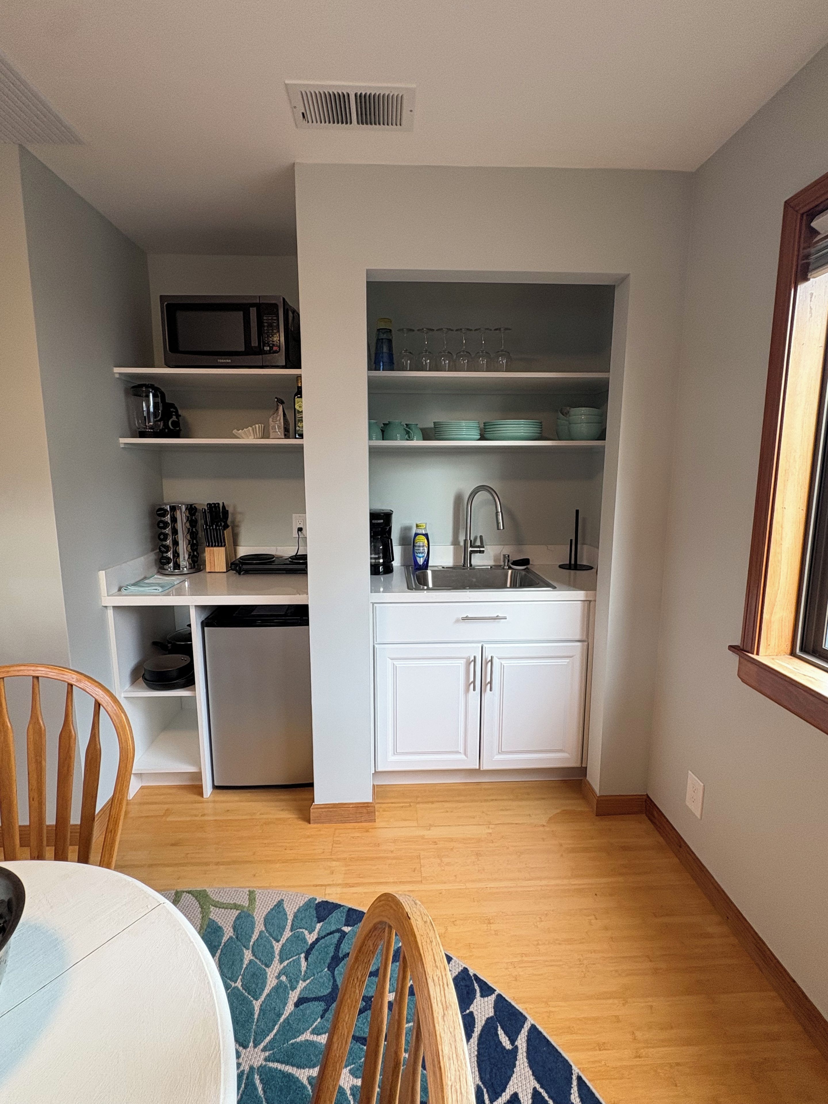 A compact kitchen with a microwave, coffee maker, and cabinets.
