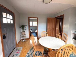 A dining area with a round table and wooden chairs, a potted plant, and a rug with a welcome mat. - Sweet and Private Apartment Close to Everything Beautiful and Fun! (El Granada)