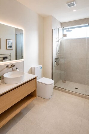 Ein modernes Badezimmer mit einer Duschkabine, einem weißen Waschbecken und einer Toilette.