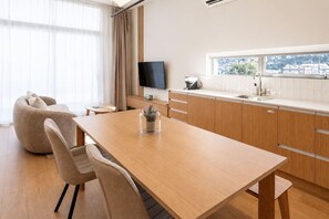 Eine moderne Küche mit einem Holztisch, Stühlen und einem Fernseher.