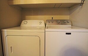A compact laundry area with a front-loading washer and a top-loading dryer. - Bear Kottage Creekside Cabin (Bryson City)