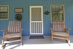 A porch with two wooden Adirondack chairs, a white door with a glass panel, and a number '95' on the wall. - Captain's Bend Creekside Cabin (Bryson City)