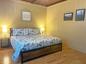 A bedroom with a bed, two bedside lamps, a framed inspirational quote, and two framed pictures on the wall. - The Cedar Post Lodge at Deep Creek (Bryson City)