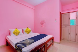 Un dormitorio con cama, almohadas, un adorno de árbol en la pared y un armario.