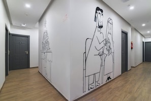 A hallway with a large wall mural depicting a stylized human figure. - THE NEW VIEW HOTEL INN (Thiruvananthapuram)