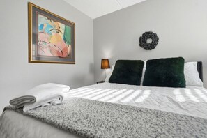 Ein Hotelzimmer mit einem Bett, einem Gemälde, einer Wandleuchte und einem dekorativen Kranz.