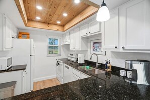Eine moderne Küche mit weißen Schränken, einer Granit Arbeitsplatte und einer Holzbalkendecke.