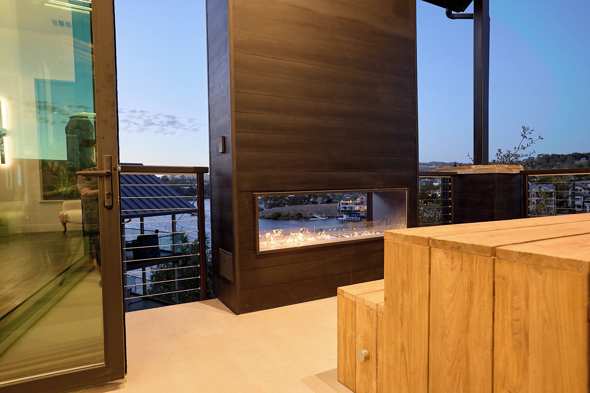 A modern outdoor seating area with a wooden table and a built-in fire feature.