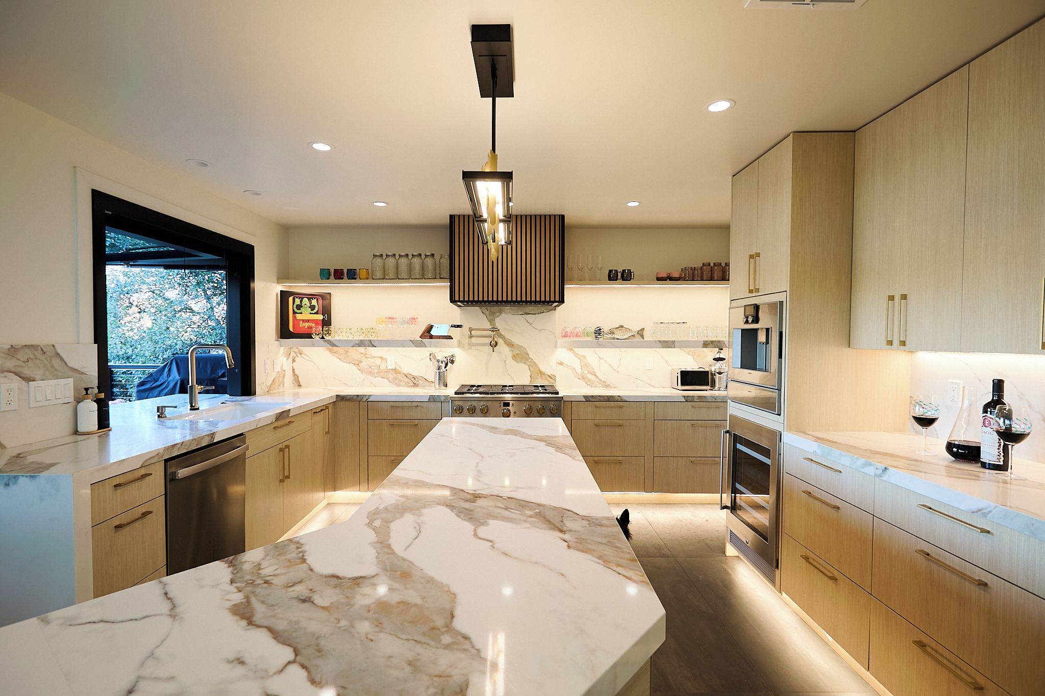 A modern kitchen with a central island, built-in appliances, and a view to the outdoors.