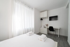 A hotel room with a bed, a desk, a chair, and a TV. - GuestReady - Urban Studio in Barrio del Pilar (Madrid)