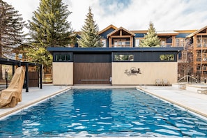 A swimming pool with a wooden deck, a covered seating area, and a building with a sign reading 'Park Station.' - Historic Old Town condo with ski access, pool, hot tub, and mountain views. (Park City)