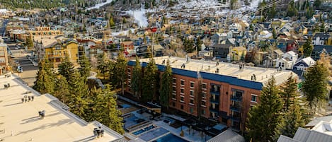 Une ville où se côtoient des bâtiments résidentiels et commerciaux, avec une piste de ski en arrière-plan et un espace piscine.