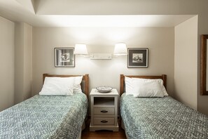 A twin bedroom with two single beds, a nightstand with a lamp, and two framed pictures on the wall. - Historic Old Town 2BR/2BA condo with hot tub, pool, sauna & walk-to-lift access. (Park City)