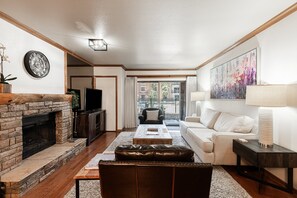 A living room with a fireplace, a television, a sofa, and a coffee table. - Historic Old Town 2BR/2BA condo with hot tub, pool, sauna & walk-to-lift access. (Park City)