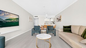 Ein modernes Wohnzimmer mit einer Couch, zwei Sesseln, einem Couchtisch und einem Essbereich mit Stühlen und einem Tisch.