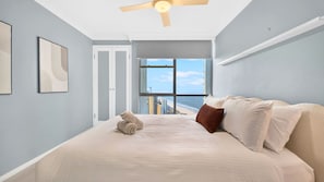 A bedroom with a bed, a ceiling fan, a view of the ocean, and a door leading to another room. - Lvl 32- Ocean Views -Sleeps 6- Parking (Surfers Paradise)