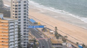 Een kustweg met uitzicht op het strand, een bord met Queensland Government en een weg naar een strandgebied.