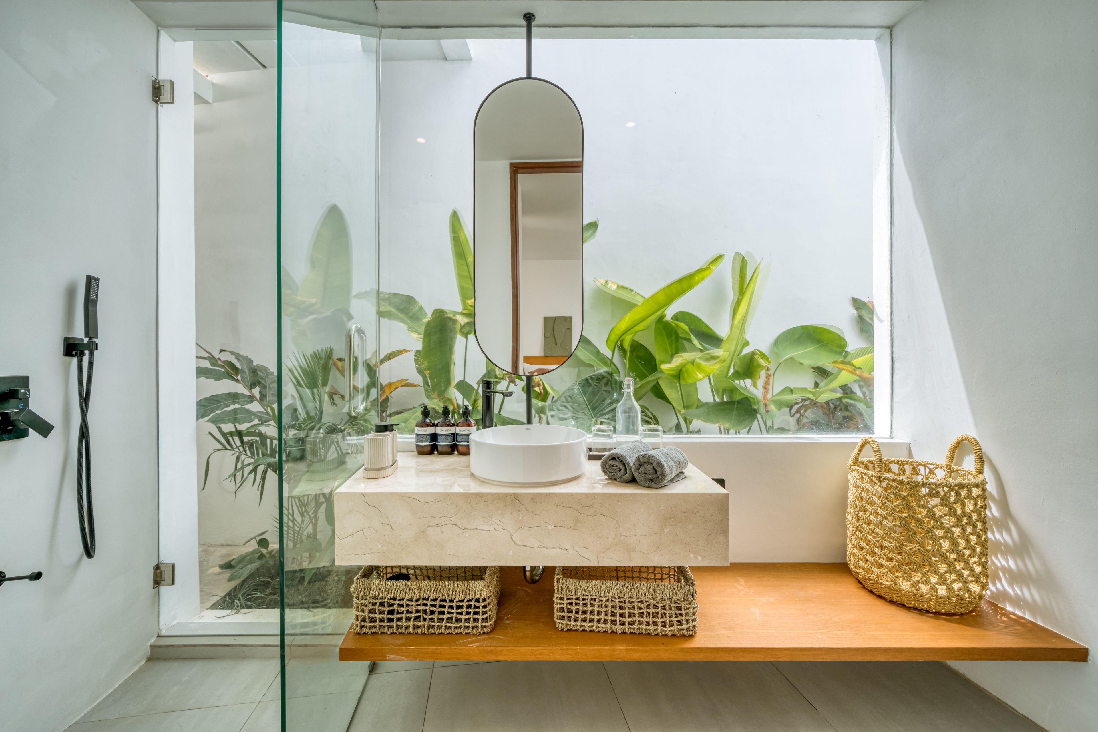Un baño moderno con cabina de ducha de vidrio, un lavamanos blanco y un espejo grande.