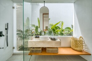 Un baño moderno con cabina de ducha de vidrio, un lavamanos blanco y un espejo grande.