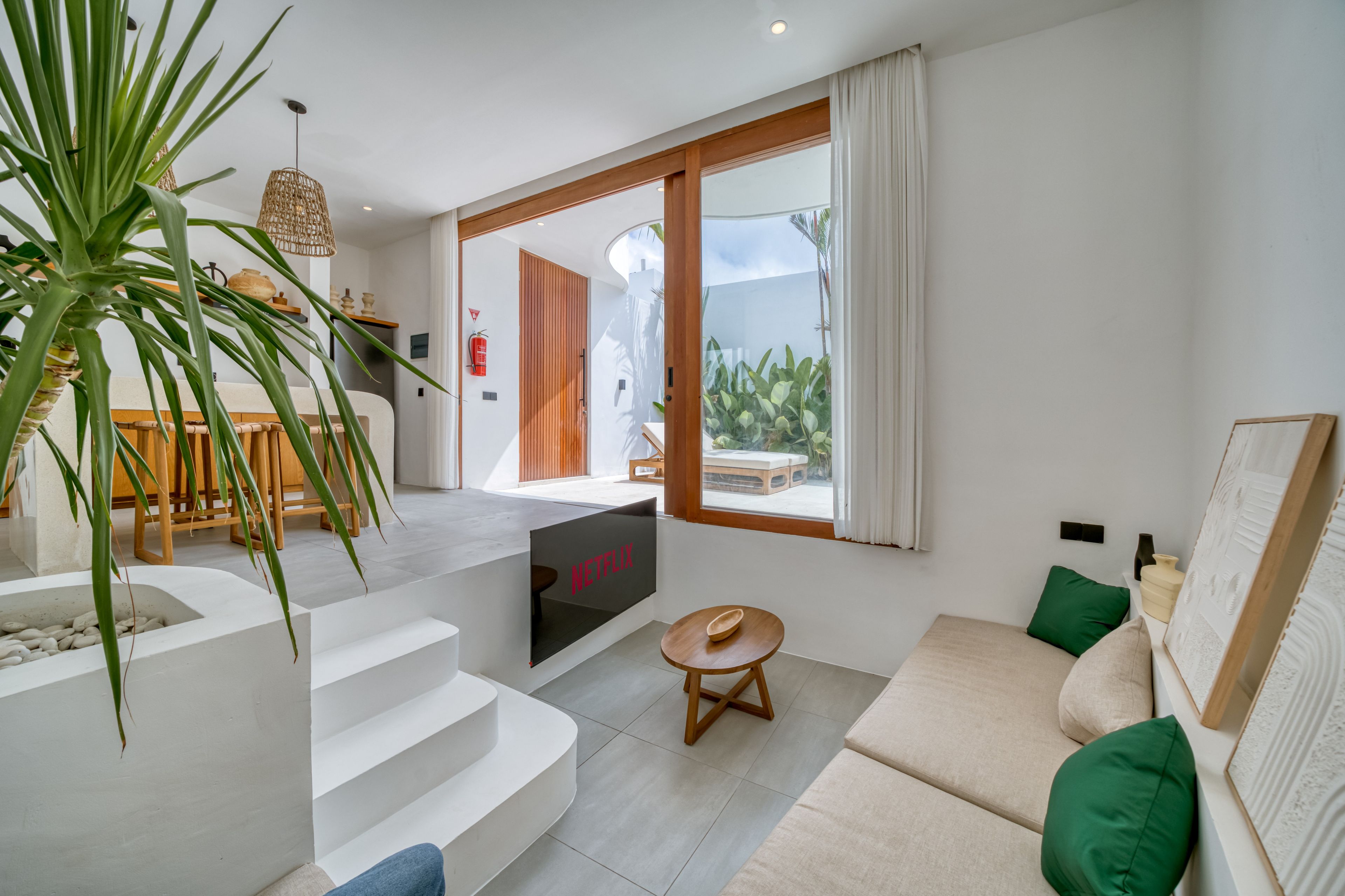 Una sala de estar moderna con un sofá, una mesita y una escalera que lleva a un balcón.