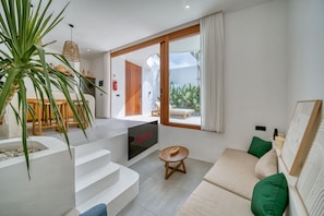 Una sala de estar moderna con un sofá, una mesita y una escalera que lleva a un balcón.