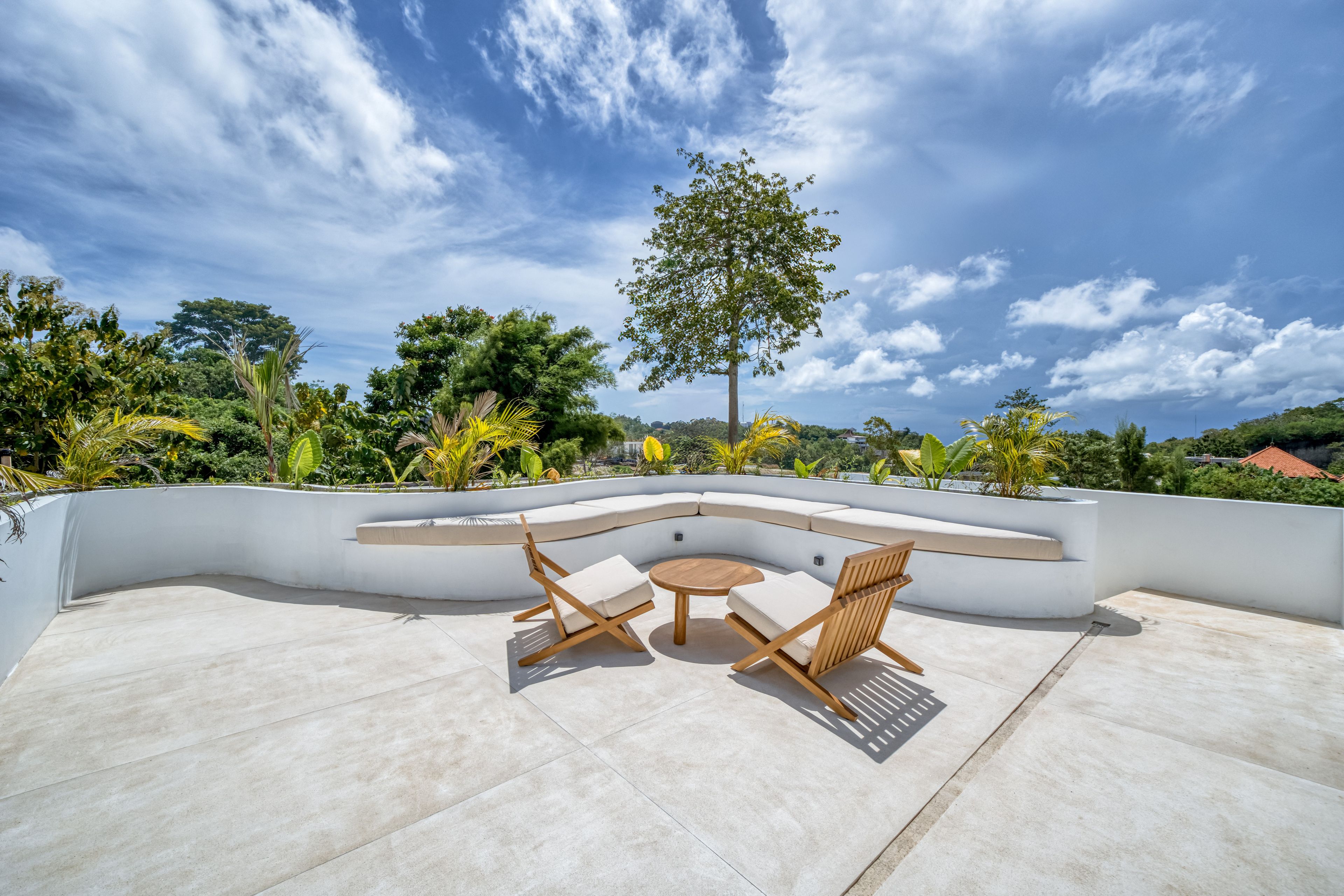 A rooftop terrace with a curved seating area, two wooden chairs, and a round table.