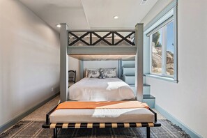 A bunk bed with a wooden headboard, a window with a view of rocks, and a carpeted floor. - Summit Lakehouse -   Luxe Home, Sleeps 39, Game Room, Yard, Fire Pit! (Fish Haven)