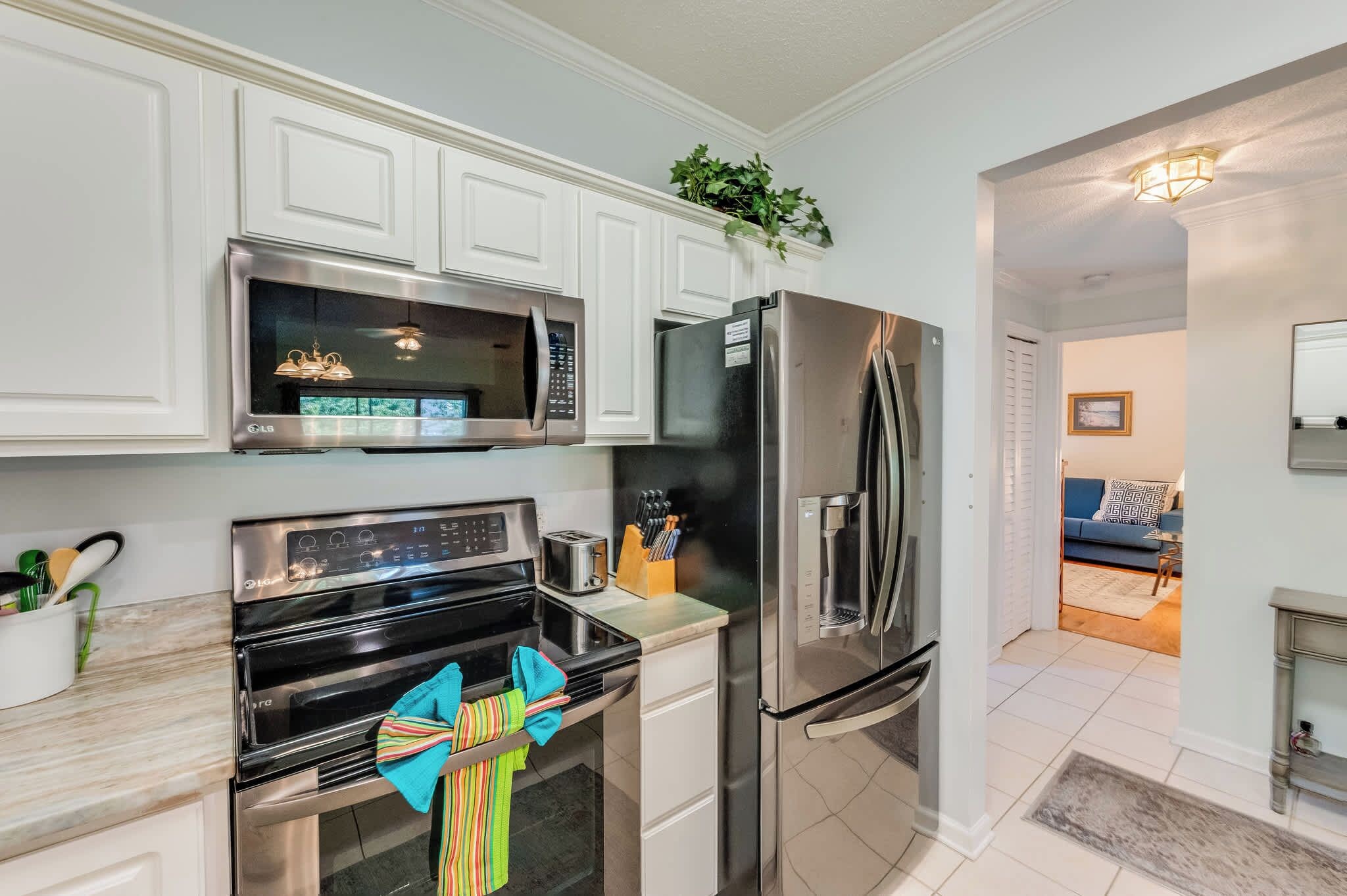 A modern kitchen with stainless steel appliances, white cabinetry, and a view into the living area.