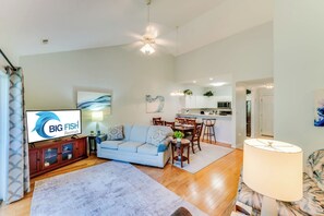 Una sala de estar moderna con un sofá, televisor y un comedor con sillas y una mesa.