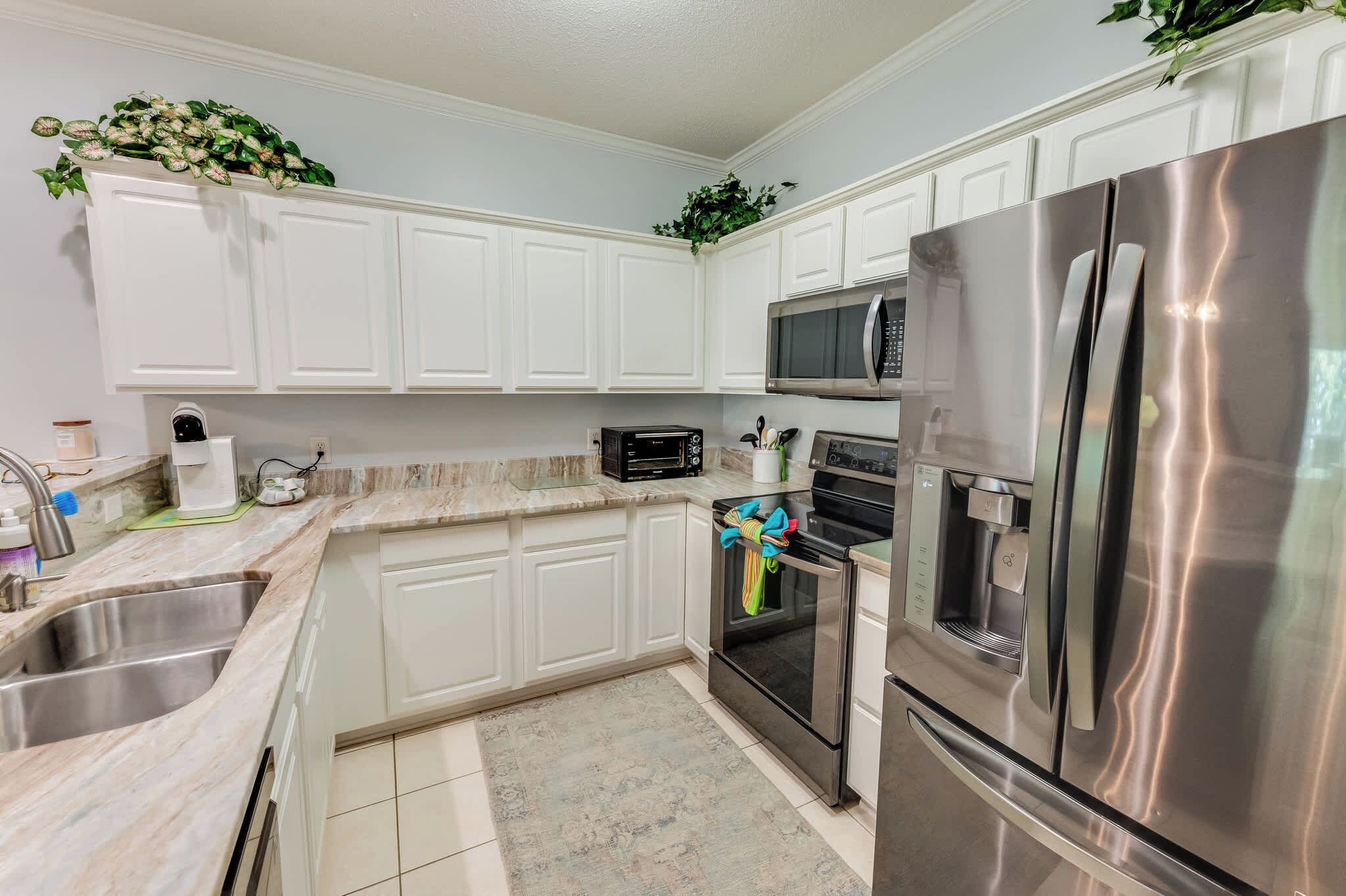 A kitchen with white cabinets, stainless steel appliances, a microwave, oven, and a refrigerator.