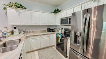A kitchen with white cabinets, stainless steel appliances, a microwave, oven, and a refrigerator.