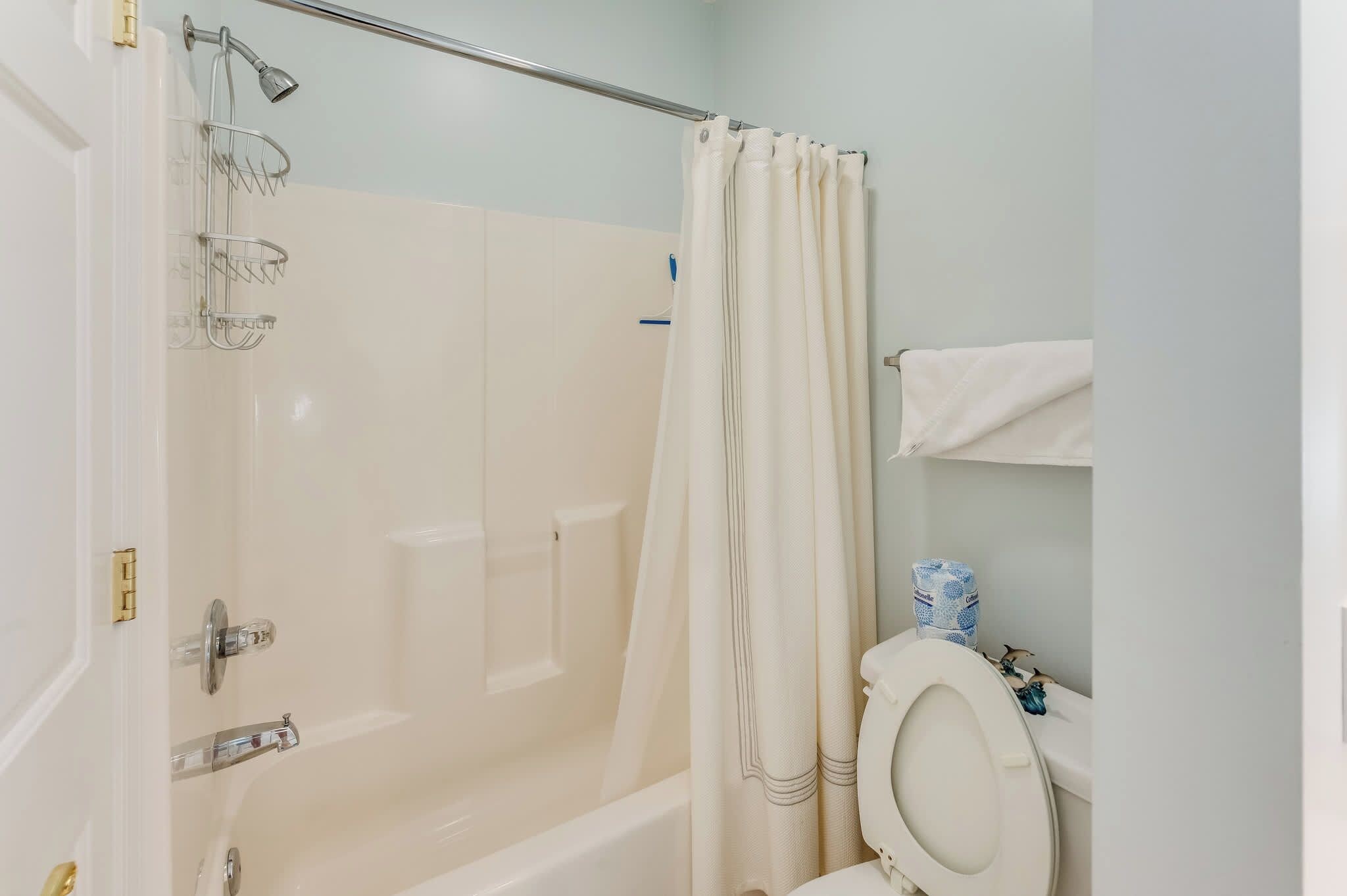 A bathroom with a bathtub, shower, toilet, and a towel rack.