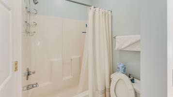 A bathroom with a bathtub, shower, toilet, and a towel rack.