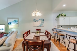 Un salon moderne comprenant un coin repas, une cuisine et un téléviseur diffusant des publicités pour « FISH Rentals ».
