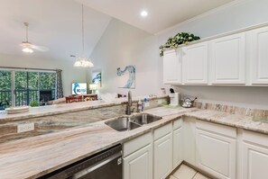Una cocina moderna con una isla grande, armarios blancos y vistas al exterior.