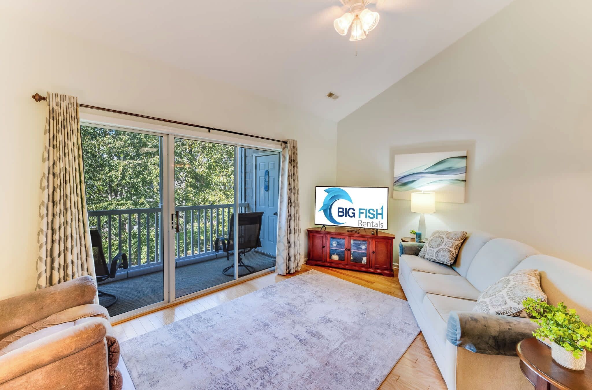 A living room with a sofa, a TV, a wooden cabinet, and a sliding glass door leading to a balcony.