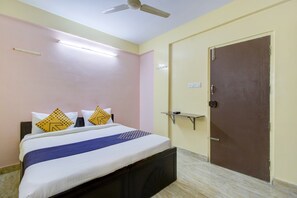 A hotel room with a bed, a ceiling fan, a door, and a wall-mounted shelf. - Hotel O Manyata Deluxe (Bangalore)