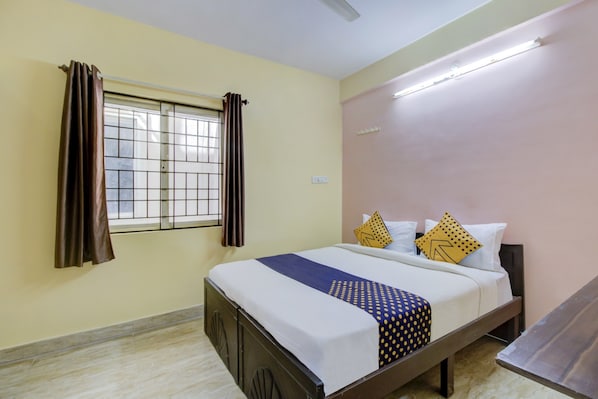 Habitación de hotel con cama, cortinas, ventana y mesita de noche.