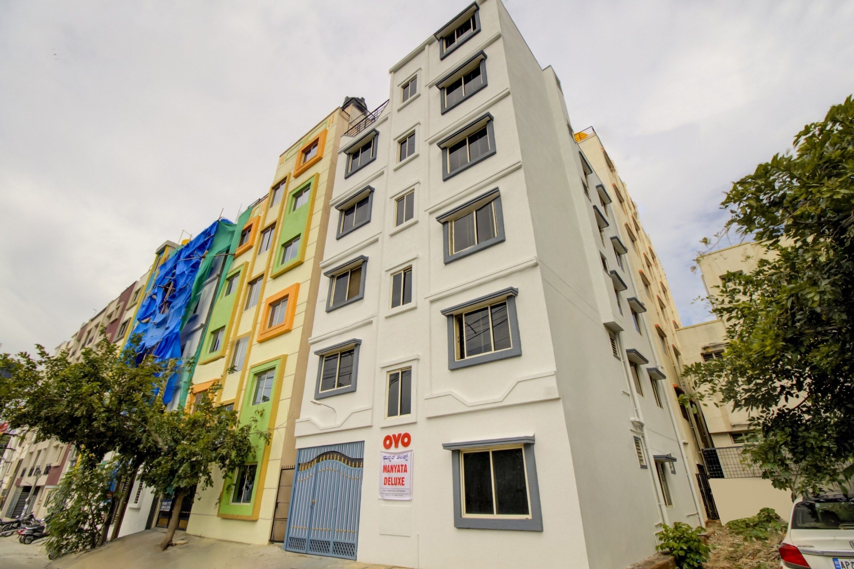 Un edificio de varios pisos con diferentes estilos de ventanas y una entrada protegida por una reja.