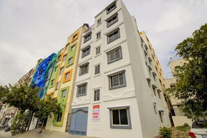 A multi-story building with a variety of window styles and a gated entrance. - Hotel O Manyata Deluxe (Bangalore)