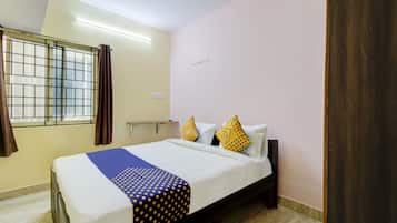 Habitación de hotel con cama, ventana con cortinas, ventilador de techo y lámpara en la pared.