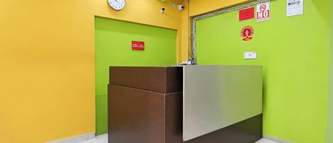 A reception area with a reception desk, a clock, and a green wall with a fire safety sign.