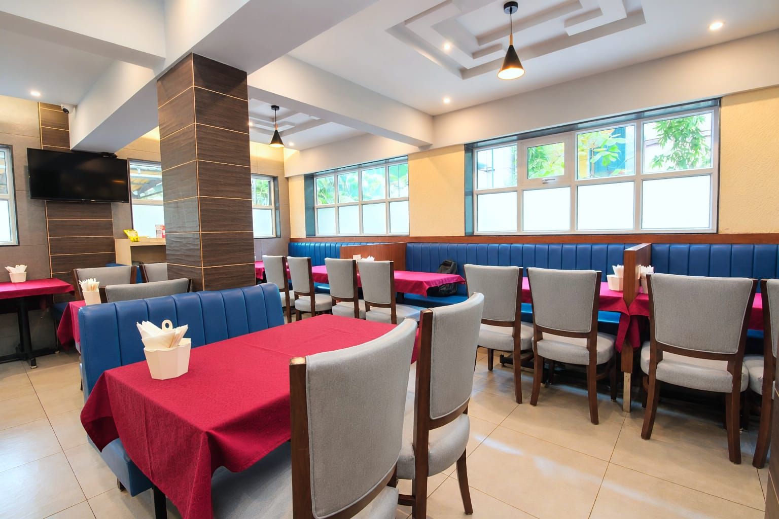 A restaurant with booths and tables, a flat-screen TV, and large windows.
