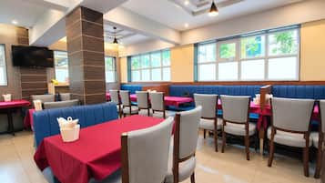 A restaurant with booths and tables, a flat-screen TV, and large windows.