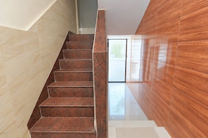 A staircase with a polished granite finish, leading to a bright interior space with a large window.