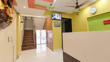 A reception area with a reception desk, a clock, and a television on the wall.